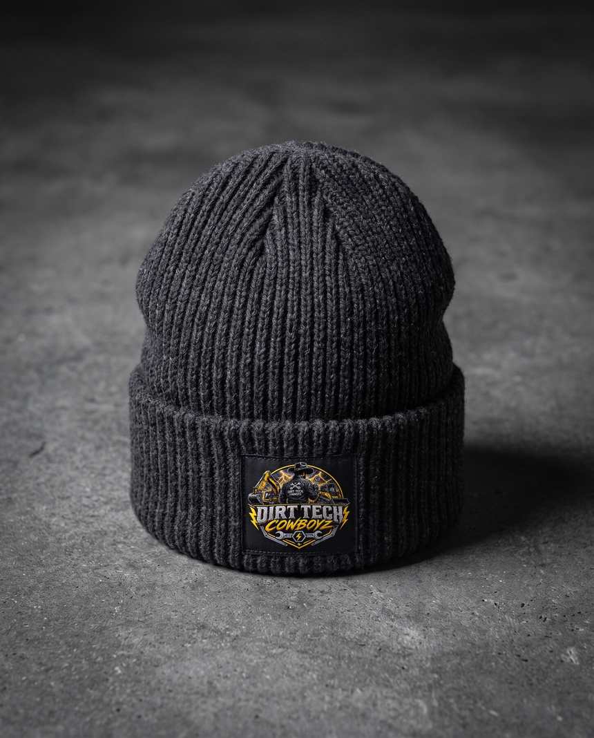Charcoal heather Dirt Tech Cowboyz cuffed knit beanie on dark concrete.
